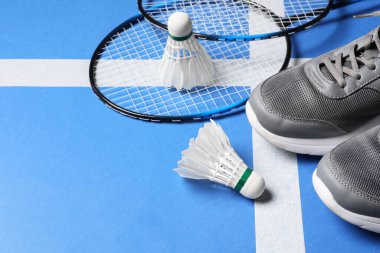 Tüylü badminton mekikleri, raketler ve spor ayakkabıları kortta, mesaj için yer
