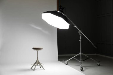 Modern stüdyoda beyaz fotoğraf, tabure ve profesyonel ışıklandırma ekipmanları