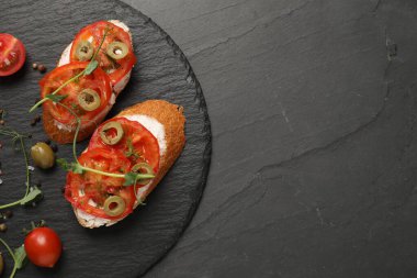 Lezzetli ricotta bruschettalar dilimlenmiş domates, zeytin ve yeşillikler siyah masada, üst manzara. Metin için boşluk