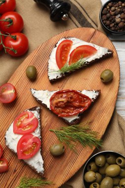 Lezzetli bruschettalar, ricotta peyniri, dereotu, zeytin, taze ve güneşte kurutulmuş domatesler masada, düz yerde.