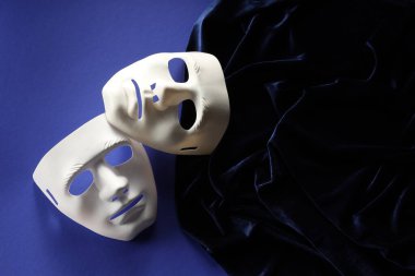 Tiyatro sanatları. Mavi arka planda beyaz maskeler ve kumaşlar, üst görünüm