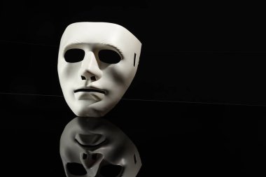 Siyah ayna yüzeyinde plastik yüz maskesi, metin için boşluk. Tiyatro performansı