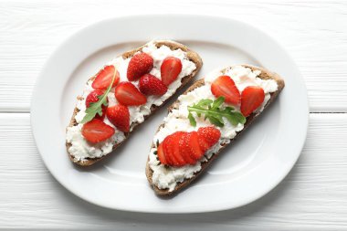 Lezzetli ricotta bruschetta çilekli ve roka beyaz ahşap masa, üst manzara