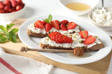 Lezzetli ricotta bruschetta çilekli, naneli, şam fıstıklı beyaz masada bal ile servis edilir.