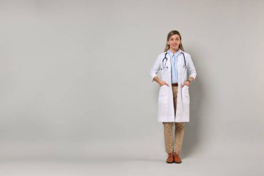 Açık gri arka planda steteskoplu mutlu doktor portresi, metin için boşluk