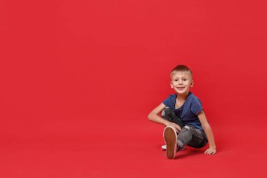 Kırmızı arka planda dans eden mutlu küçük çocuk. Metin için boşluk