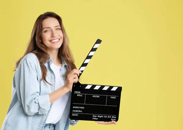 stock image Making movie. Smiling woman with clapperboard on yellow background. Space for text