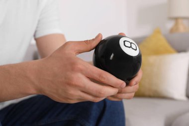 Sihirli sekiz topu tutan adam kapalı alanda, yakın plan.