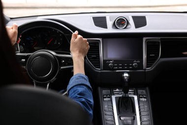 Woman holding steering wheel while driving her car, closeup