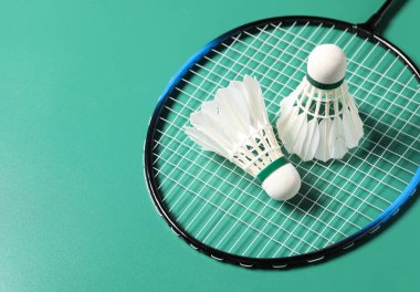 Badminton mekikleri ve raketleri yeşil arka planda tut. Metin için boşluk