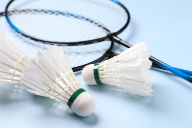 Tüy badminton mekik horozları ve raketler açık mavi arka planda, yakın plan