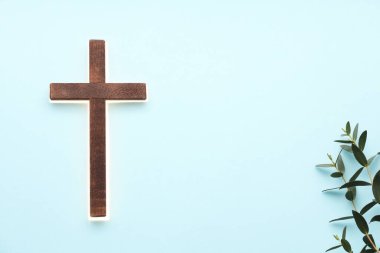 Parlak haç ve okaliptüs dalları açık mavi arkaplanda, metin için boşluk. Hıristiyanlık Dini