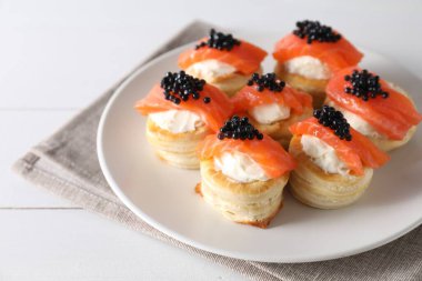 Krem peynirli lezzetli puf böreği, somon balığı ve beyaz ahşap masada siyah havyar.