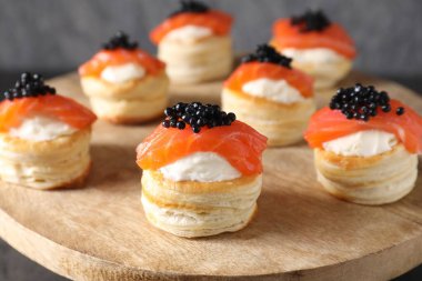 Krem peynirli lezzetli puf böreği, somon balığı ve siyah havyar ahşap tezgahta, yakın plan.