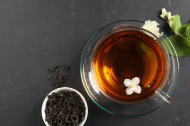 Cam bardakta Aromatik yasemin çayı, gri masada çiçekler ve kuru yapraklar, üst manzara