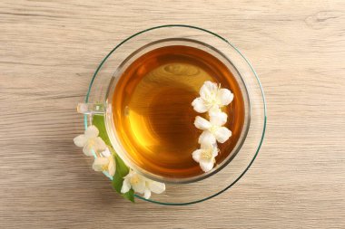Aromatik yasemin çayı fincanda ve çiçekler ahşap masada, üst tarafta.