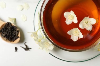 Sıcak yasemin çayı fincanda ve çiçekler beyaz mermer masada, düz yerde.