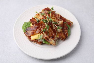 Pastırmalı lezzetli sandviç ve açık gri masada mikro yeşiller.