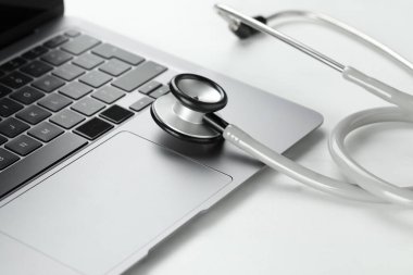 Modern laptop ve steteskop beyaz masada, yakın plan.