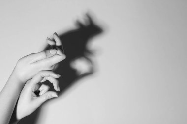 Gölge kuklası. Kadın arka plandaki tavşan gibi el hareketi yapıyor, mesaj için yeri olan bir yere yakın çekim yapıyor. Siyah ve beyaz etkisi