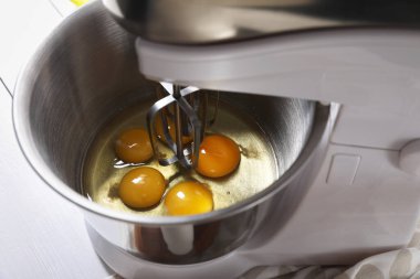 Para kazanmak. Beyaz masadaki karıştırıcı kasesinde çiğ yumurta, yakın plan.