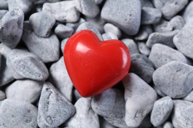 One red decorative heart on grey stones, above view