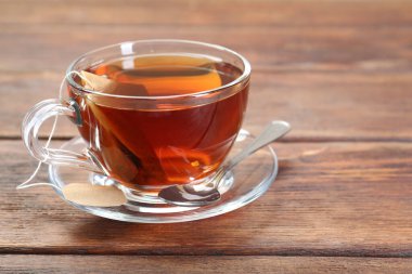 Aromatik çay demliyorum. Tahta masada çay poşeti ve kaşıkla. Metin için boşluk