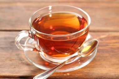 Tahta masada bir bardak çay ve kaşık.