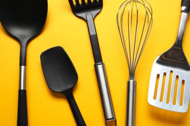 Farklı spatulalar ve turuncu arka planda çırpma, düz yatış