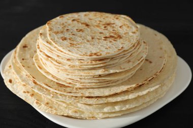 Pek çok lezzetli ev yapımı tortilla siyah ahşap masada, yakın plan.