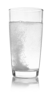 Fışkırtan haplar, beyaza izole edilmiş su bardağında çözünüyor.