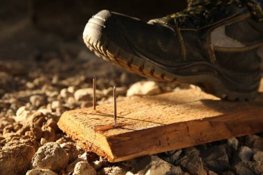 Dikkatsiz işçi tahta çivilere basıyor, yakın plan.