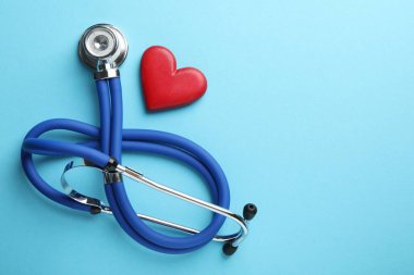 Stetoskop ve açık mavi arka planda kırmızı kalp, üst manzara. Metin için boşluk