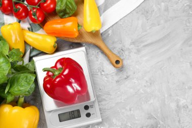 Gri desenli masa üzerinde dolmalık biber, fesleğen ve domatesli mutfak terazisi. Metin için boşluk