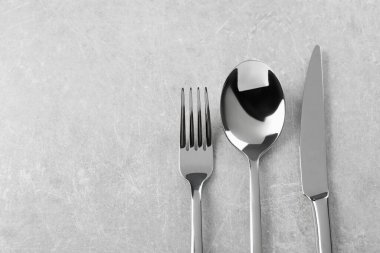 Gümüş çatal bıçak seti gri masada, düz yerde. Metin için boşluk