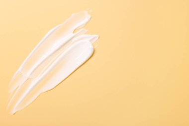 Soluk sarı arka planda yüz kremi örnekleri, üst manzara. Metin için boşluk