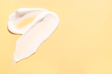 Soluk sarı arka planda yüz kremi örnekleri, üst manzara. Metin için boşluk