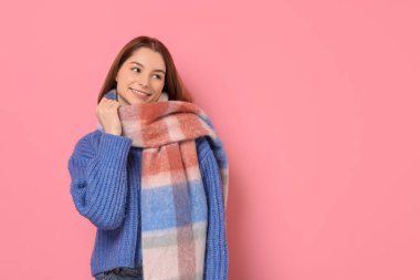Pembe arka planda sıcak eşarplı güzel kadın, metin için yer