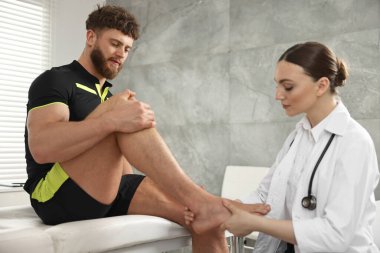 Spor sakatlığı. Hastanedeki hastanın ayağını muayene eden doktor.