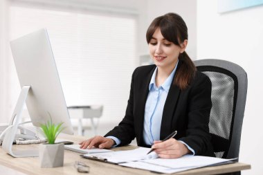 Smiling secretary working at table in office