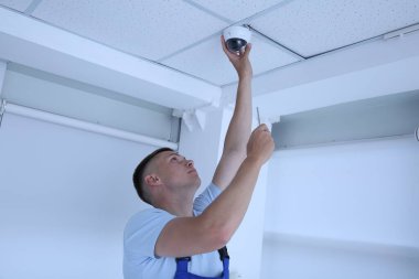 Tornavidalı teknisyen kapalı alanda güvenlik kameraları yerleştiriyor.