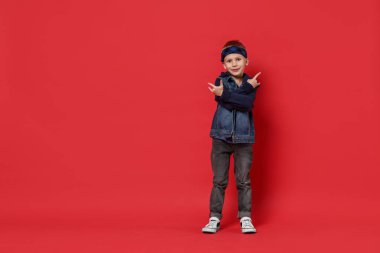 Kırmızı arka planda dans eden küçük mutlu çocuk