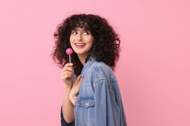 Pembe arka planda lolipopu olan güzel bir kadın.