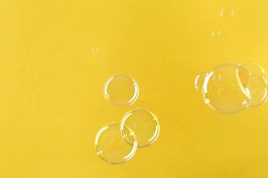 Sarı arka planda güzel şeffaf sabun köpükleri