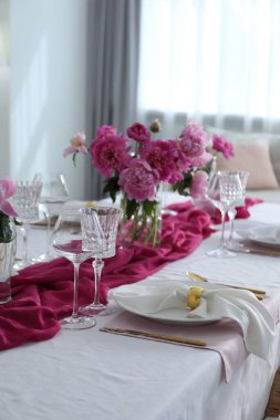 Beautiful table setting with pink peonies in dining room