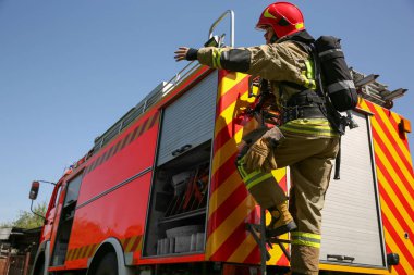 İtfaiyeci üniformalı. Dışarıdaki itfaiye aracında.
