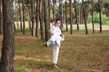 Kimonolu tatlı küçük kız ormanda karate yapıyor.