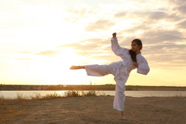 Gün batımında nehirde karate yapan kimonolu tatlı bir kız.