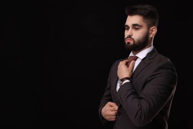 Handsome businessman in suit and necktie on black background. Space for text