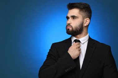 Handsome businessman in suit and necktie on blue background. Space for text